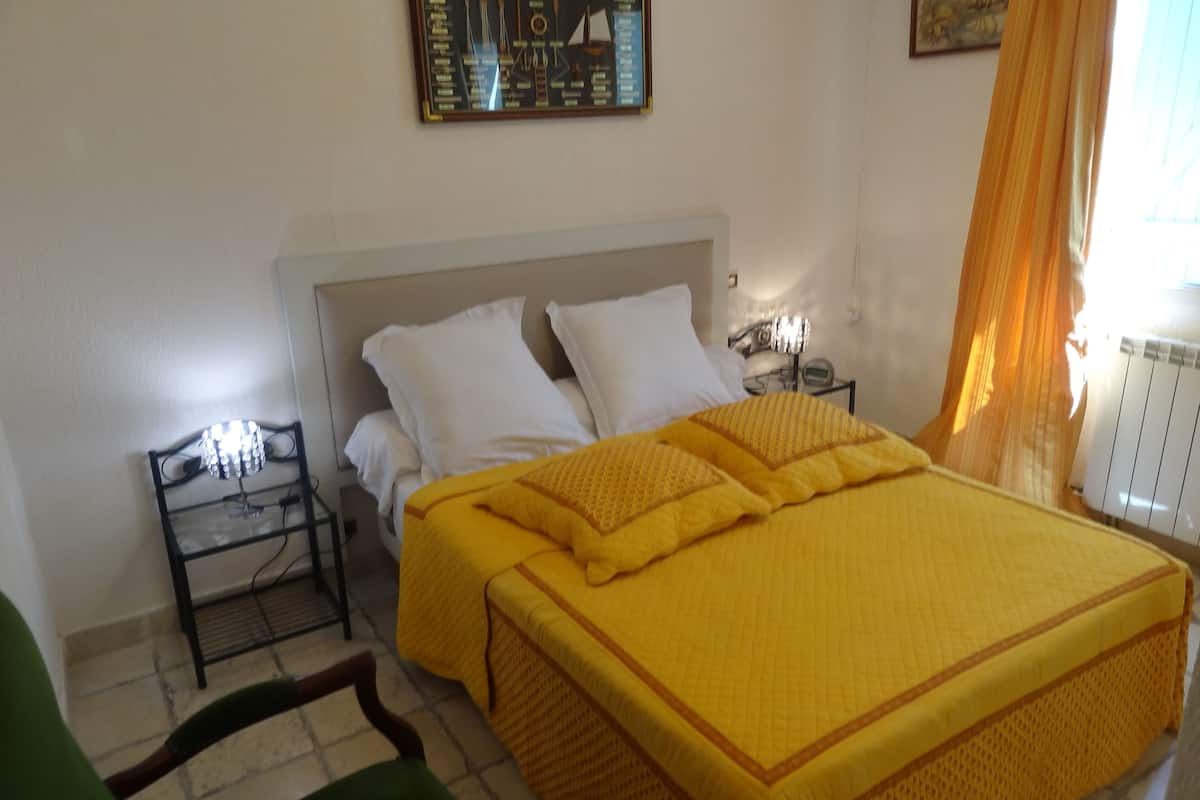 A bedroom with a bed, a nightstand, a lamp, and a chair.