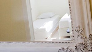 Un miroir doté d’un cadre décoratif qui reflète une chambre à coucher avec un lit et une fenêtre.