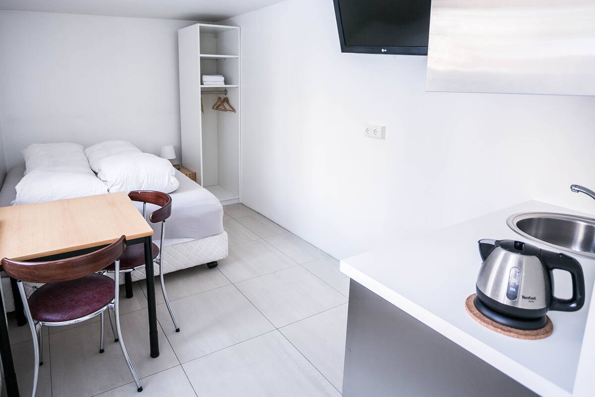 Une cuisine compacte équipée d’un évier, d’une bouilloire et d’un coin repas avec une table et des chaises.