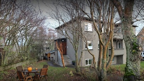Une maison à deux étages avec un escalier apparent qui mène à l’entrée.