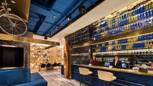 A bar area with a blue seating arrangement, a bartender, and shelves stocked with bottles. - Manxin Hotel Xian North Railway Station Municipal Government (Xi'an)
