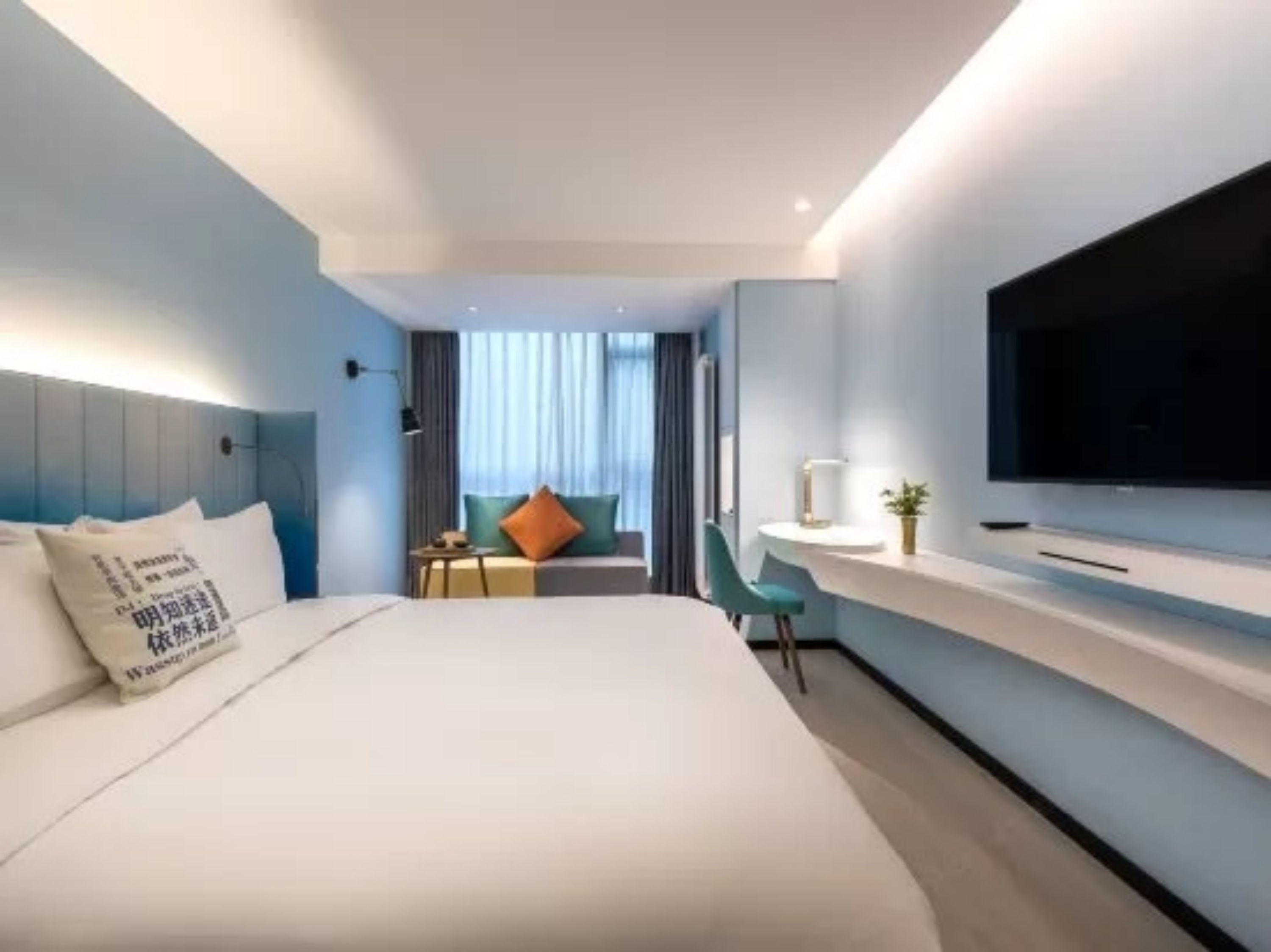 Une chambre d’hôtel moderne avec un grand lit, un bureau avec une télévision et une vue sur la ville.