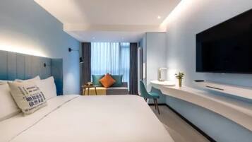 Une chambre d’hôtel moderne avec un grand lit, un bureau avec une télévision et une vue sur la ville.