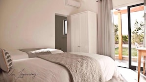 A bedroom with two beds, a wardrobe, and a sliding glass door leading to an outdoor area. - Denneboom Vineyards and Wildlife (Paarl)