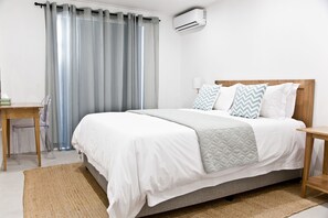 A neatly arranged bedroom with a bed, bedside tables, a desk, and a chair.