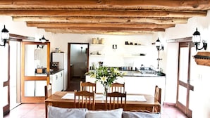 A cozy living room with a wooden ceiling, a dining table with chairs, and a leather sofa. - Denneboom Vineyards and Wildlife (Paarl)