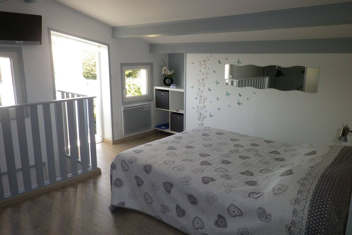 A bedroom with a bed, a desk, a chair, a window, and a balcony.