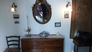 Una habitación con un aparador de madera, una silla, un espejo y una lámpara.