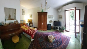 Un salón acogedor con un mueble de madera, un televisor, un tapete estampado en rojo y azul, y una mesita con un cuenco.