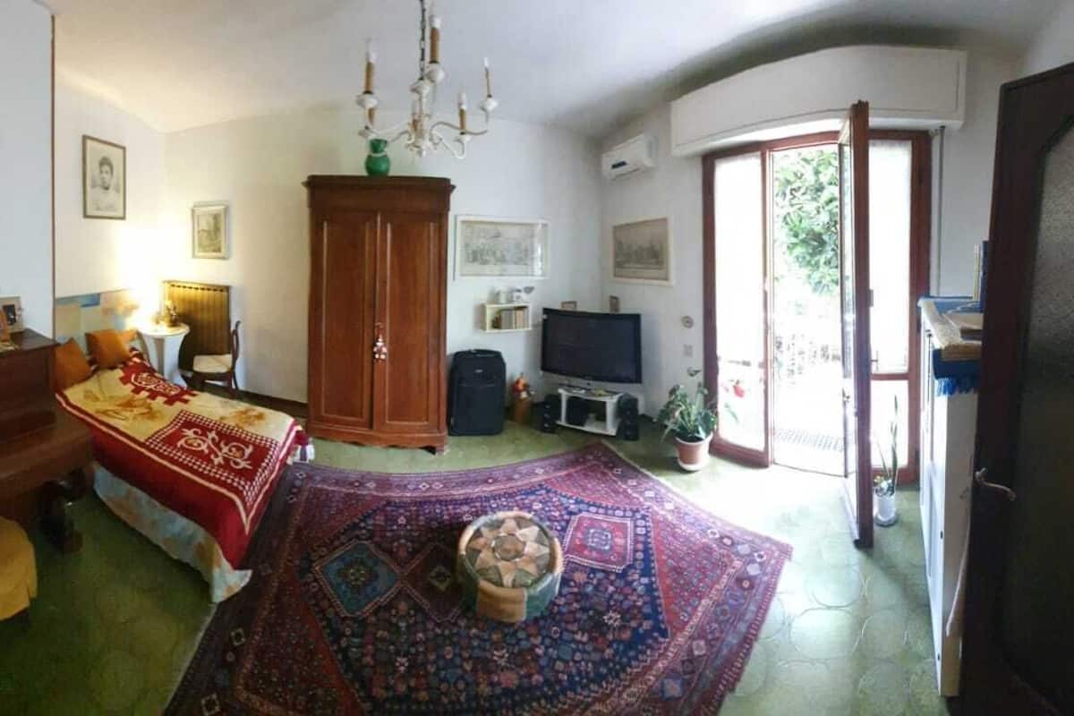 Un salón acogedor con un mueble de madera, un televisor, un tapete estampado en rojo y azul, y una mesita con un cuenco.