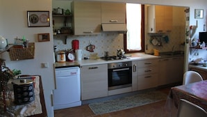 Una cocina compacta equipada con lavavajillas, horno y un pequeño comedor con mesa y sillas.