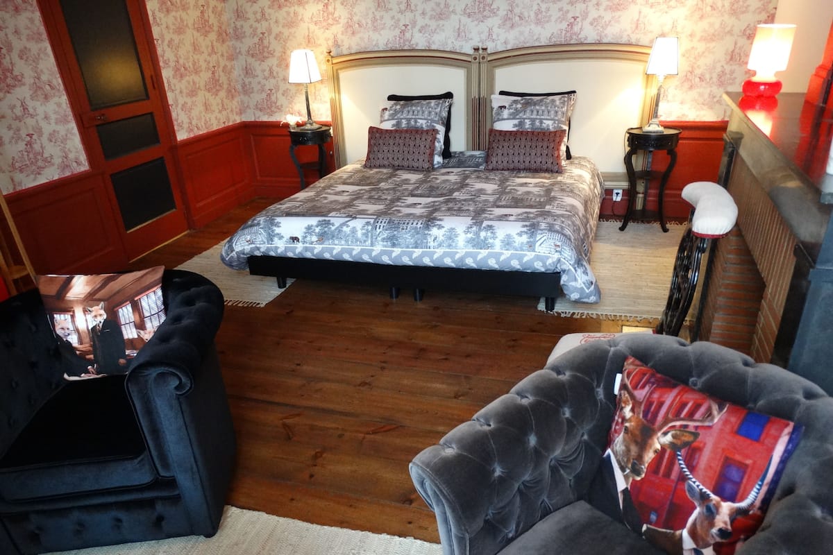 Een slaapkamer met een groot bed, twee nachtkastjes, een stoel en een bank.