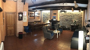 Une pièce chaleureuse avec une cheminée, un mur en pierre, des meubles en bois et une horloge au mur.