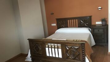 Un dormitorio con una cama de madera, una mesita de noche y un aplique de pared.