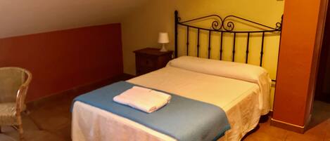 A bedroom with a bed, a chair, and a nightstand.