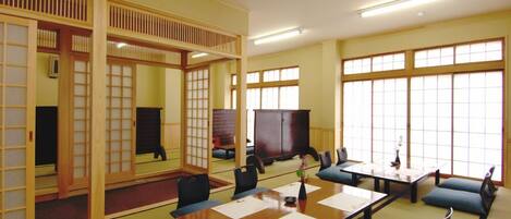 A traditional Japanese-style room with tatami flooring, low tables, and cushions.