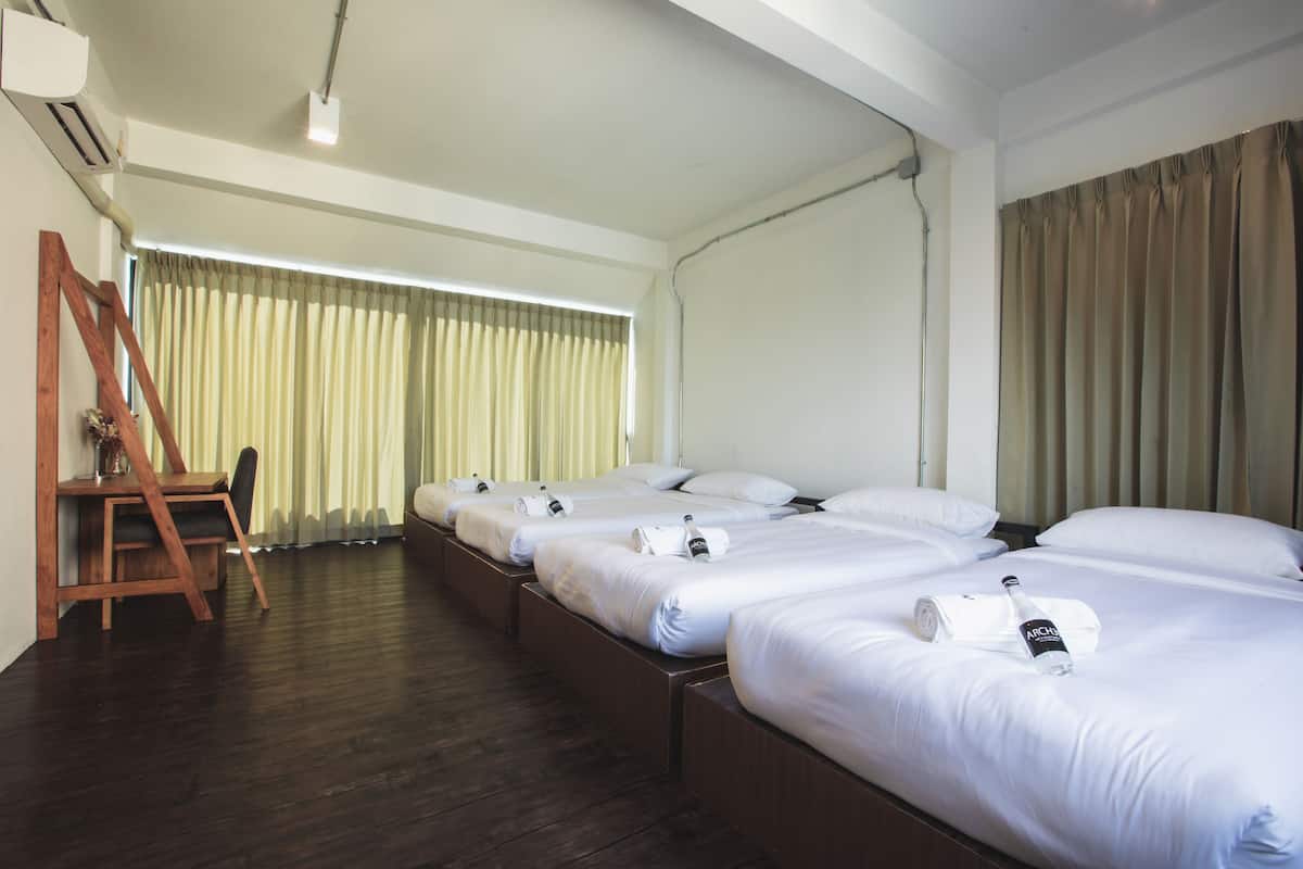A hotel room with three beds, a desk, and a chair.