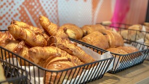 A display of various baked goods, including croissants and other pastries, arranged in metal baskets.