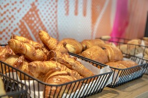 A display of various baked goods, including croissants and other pastries, arranged in metal baskets.