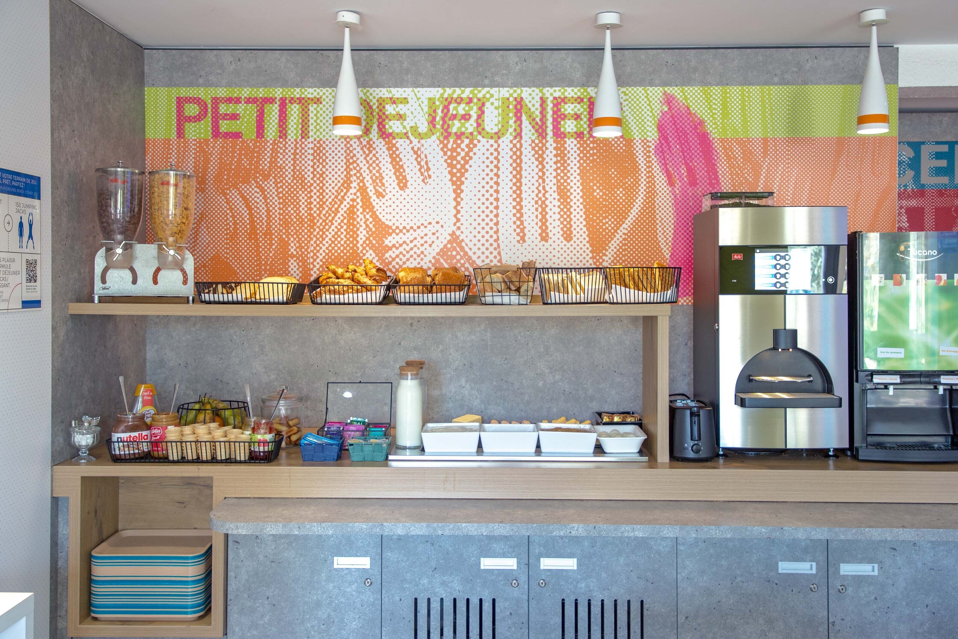 Een ontbijtbuffet met een koffieapparaat, blender en diverse soorten eten.