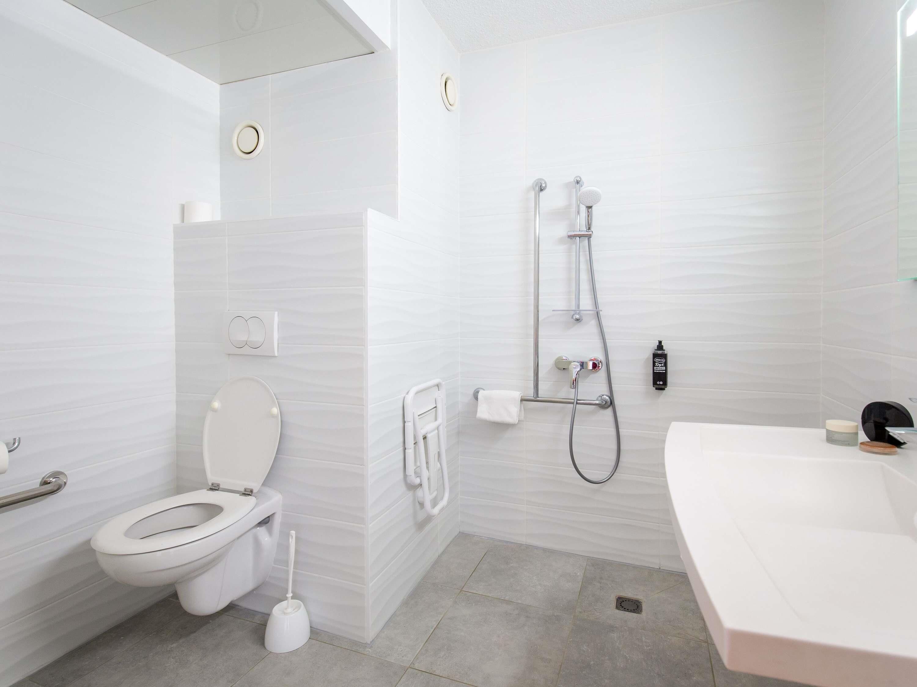 A modern bathroom with a toilet, bidet, shower, and sink.