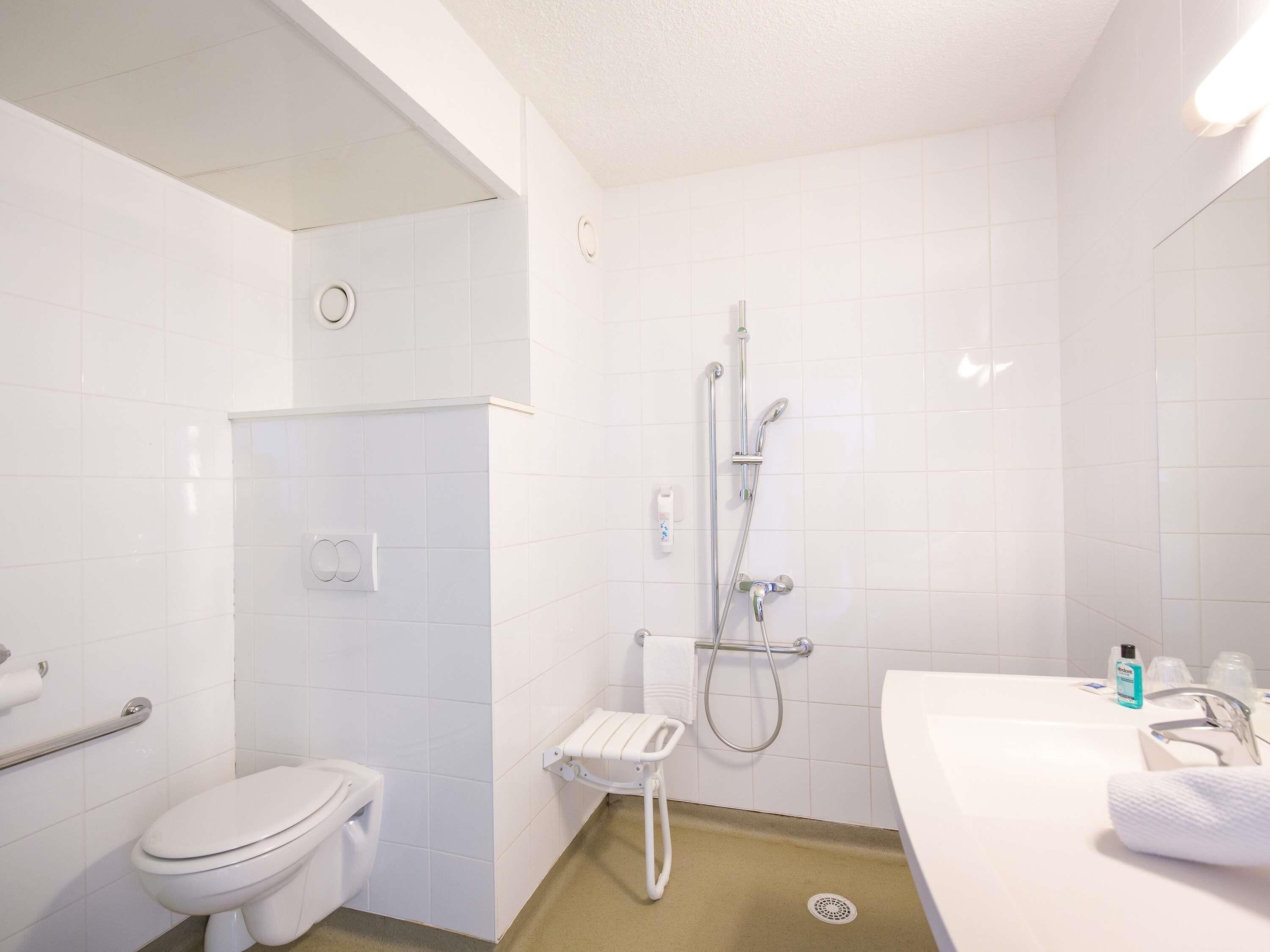 A bathroom with a toilet, a shower, and a sink.