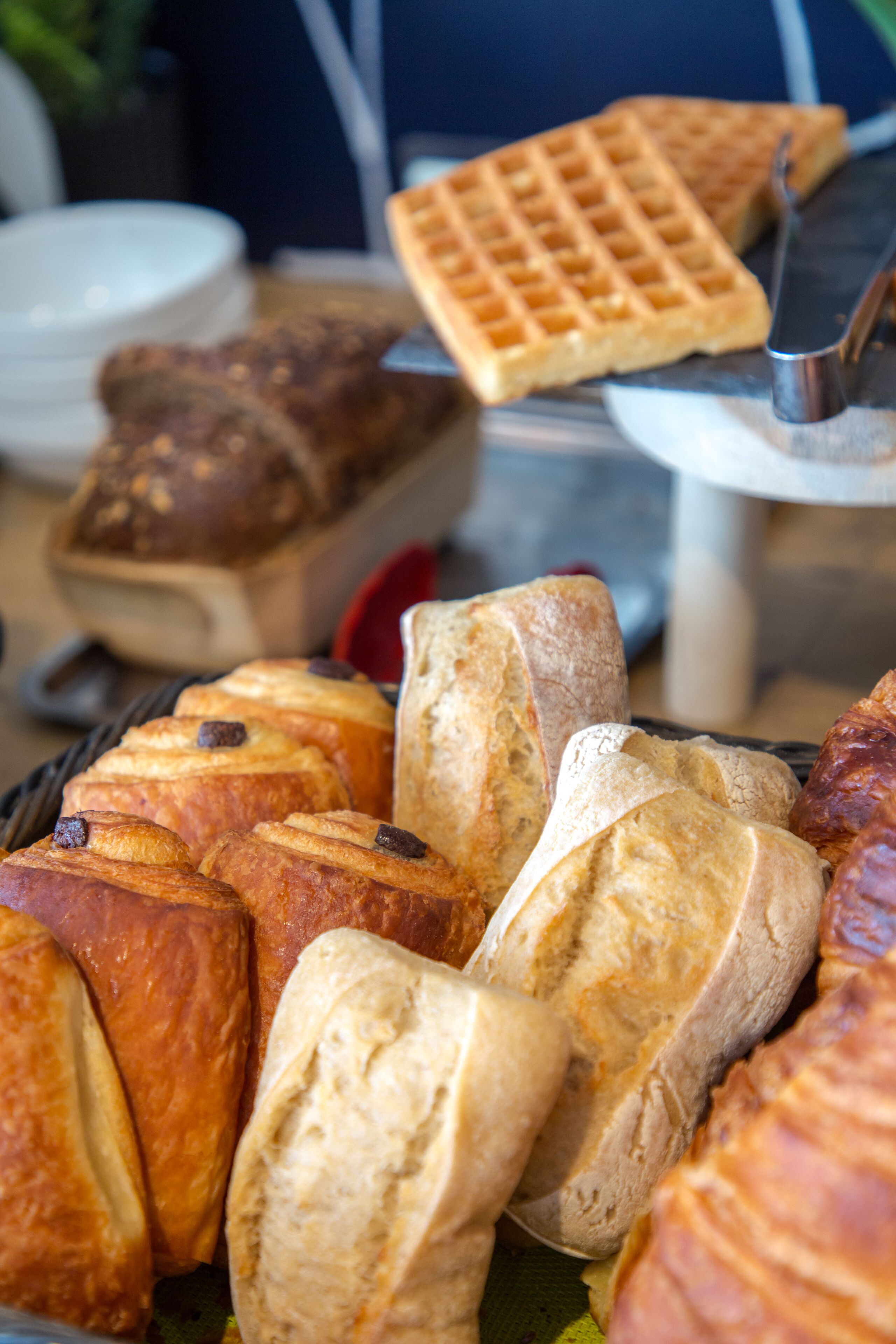 A variety of baked goods including bread, croissants, and waffles.