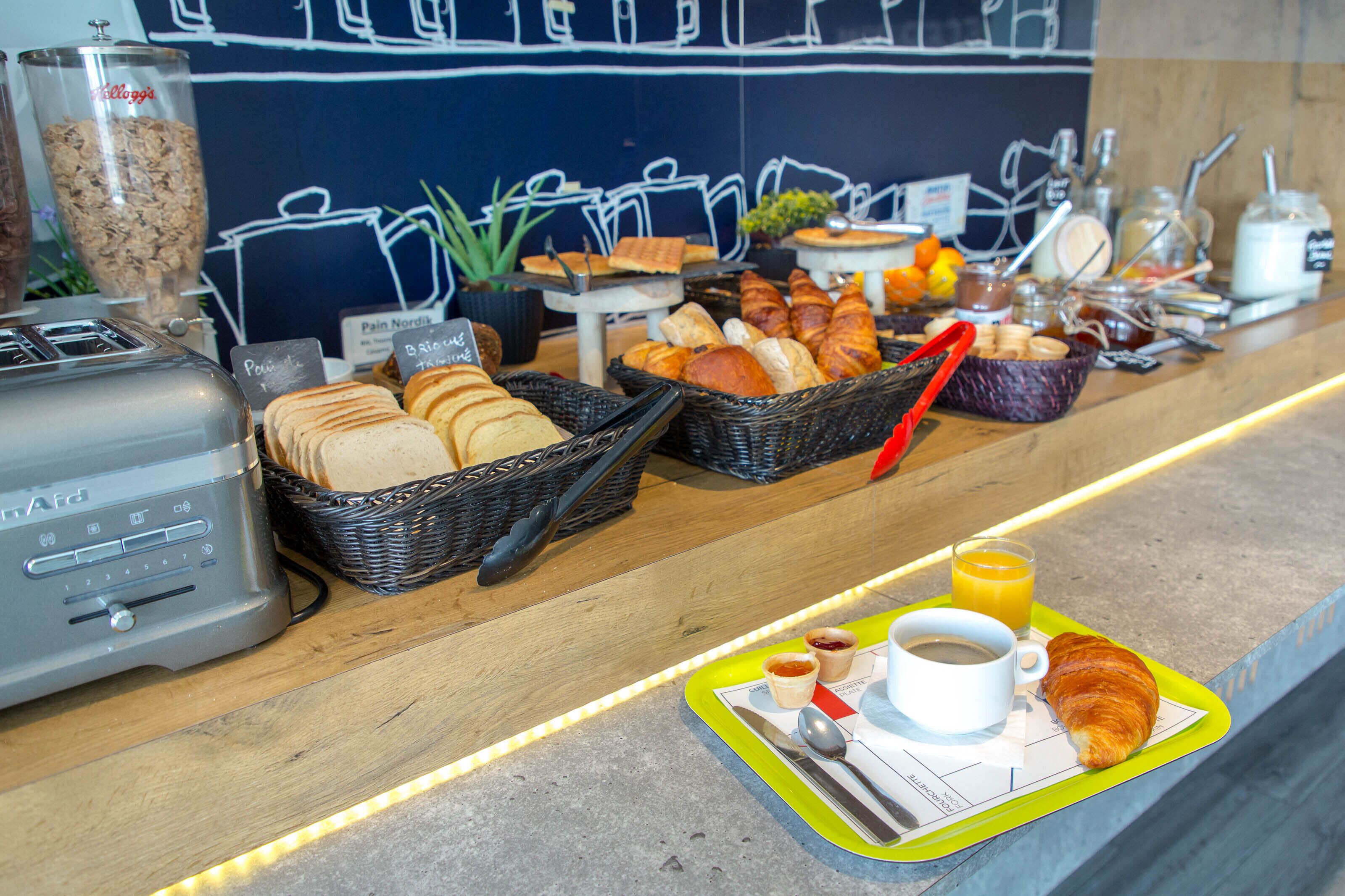 A breakfast buffet with bread, pastries, and beverages.
