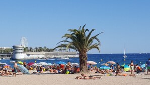 A beach with palm trees, umbrellas, and people sunbathing. - ibis budget Fréjus Saint-Raphaël Centre et Plage (Fréjus)