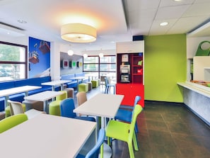 Interior de restaurant amb seients privades, taules i màquina expenedora.