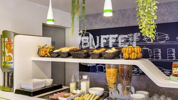 Un buffet proposant une variété de plats, une machine à café et des plantes suspendues.