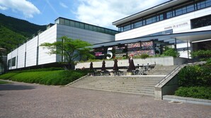 Un bâtiment moderne avec une enseigne indiquant « musée de Grenoble » et un espace extérieur aménagé avec des parasols.