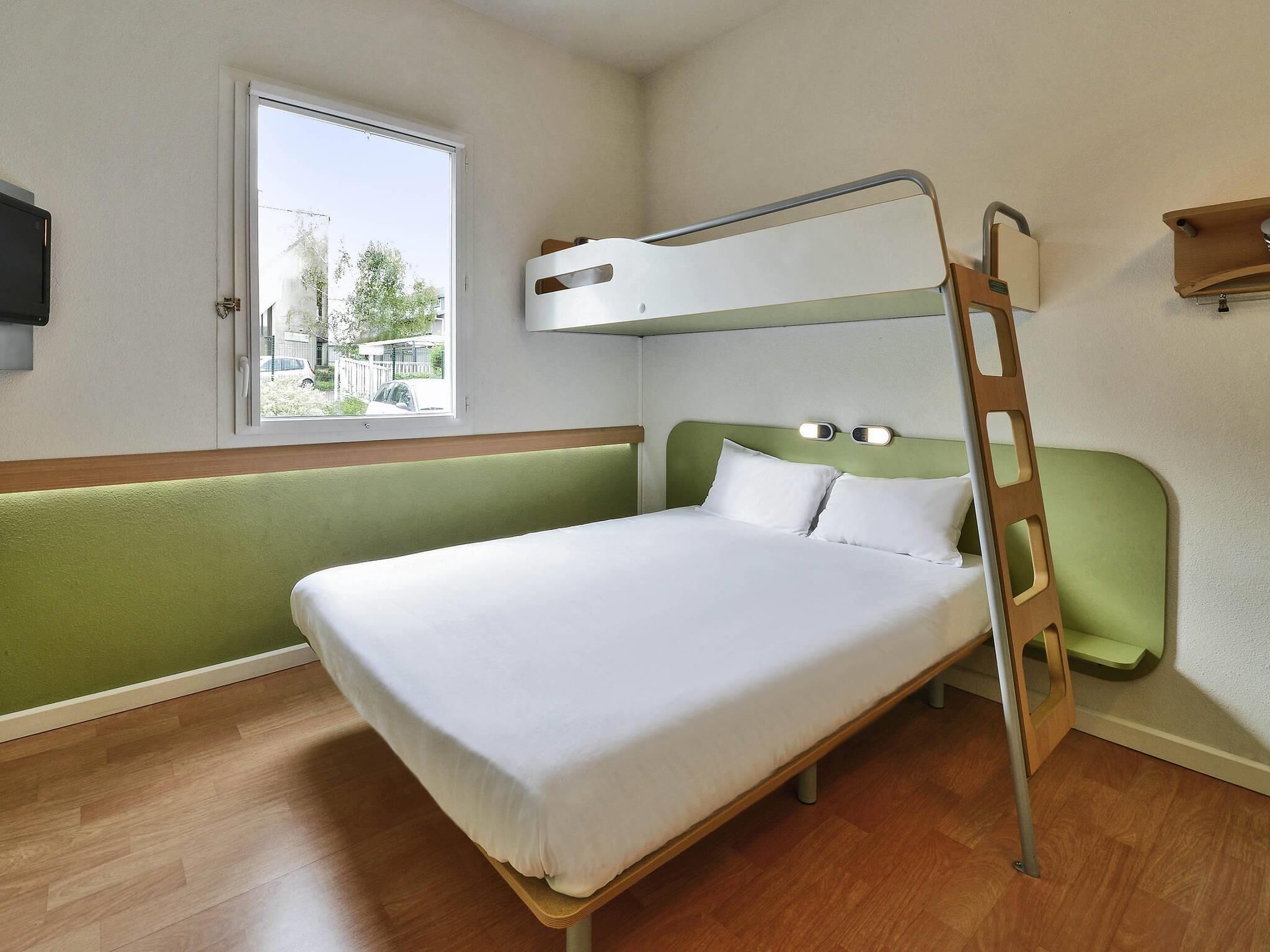 Una cama litera con una escalera, una ventana con vistas al exterior y un piso de madera.