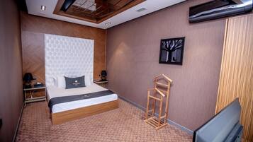 Una habitación de hotel moderna con una cama grande, un cabecero de madera, un televisor de pantalla plana y una obra de arte en la pared.