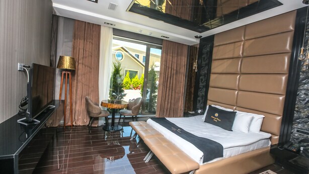 Een moderne hotelkamer met een groot bed, een bankje, een bureau en een zithoek.