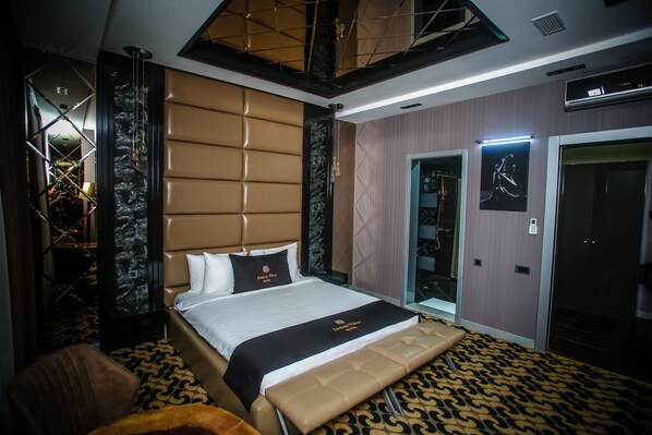 A modern hotel room with a large bed, a seating area, and a wardrobe.