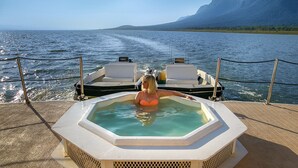 Ein Whirlpool auf einem Boot mit Blick auf Wasser und Berge im Hintergrund.