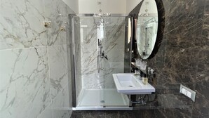 A modern bathroom with a glass-enclosed shower, a white sink, and a large mirror. - King Plaza (Rome)