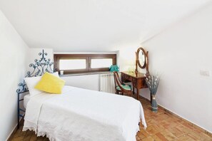 A bedroom with a bed, a dresser, a chair, a mirror, and a window.
