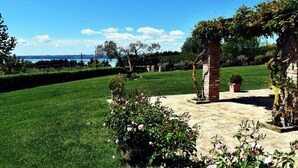 A well-maintained garden with a brick structure, a lawn, and a view of the sea. - La Cavetta Country House (Trevignano Romano)