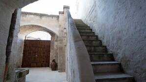 A narrow staircase with a stone balustrade, leading to a wooden door with a metal gate. - Giardini di Pietra (Matera)