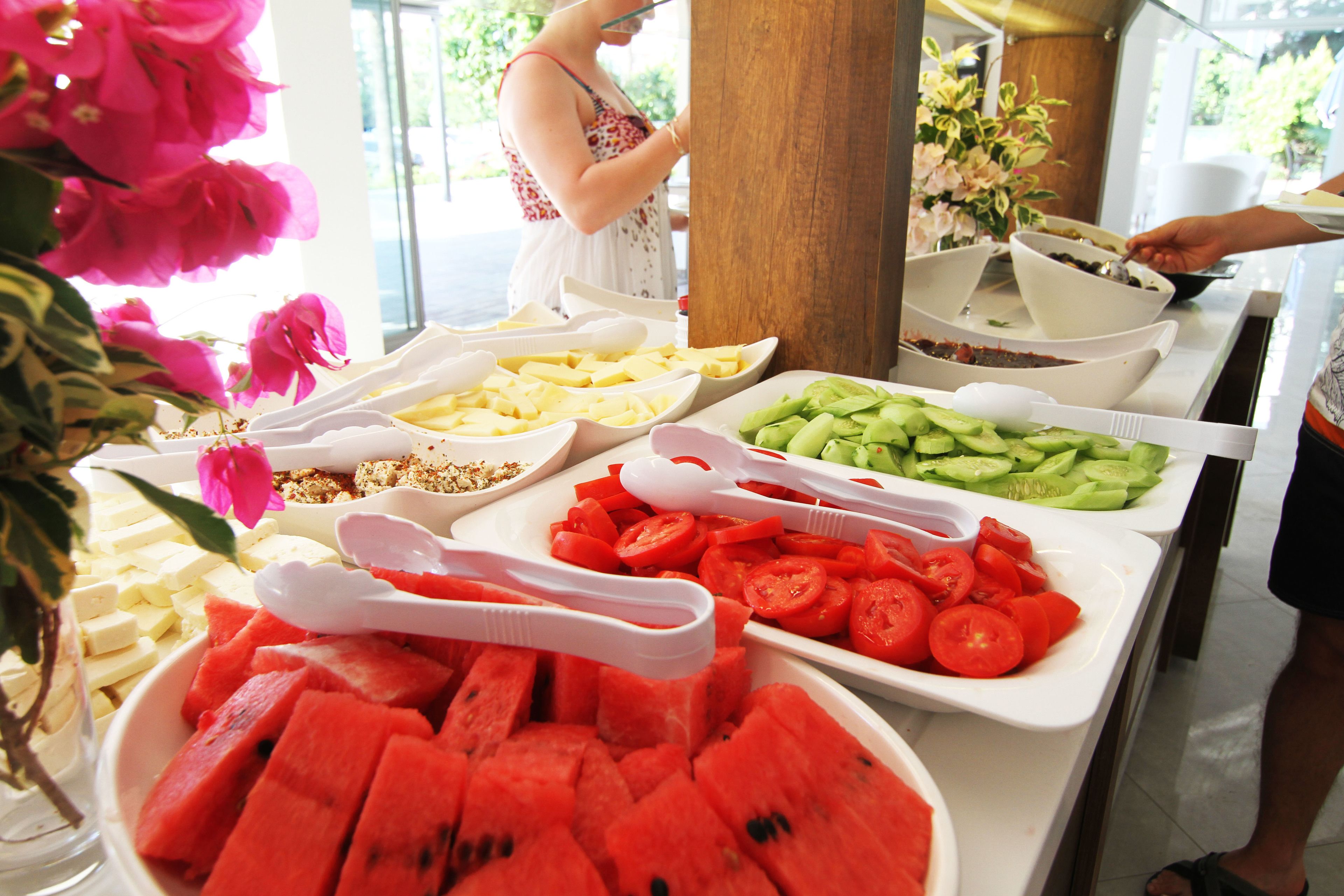 A buffet with various food items including watermelon, tomatoes, and cucumbers.