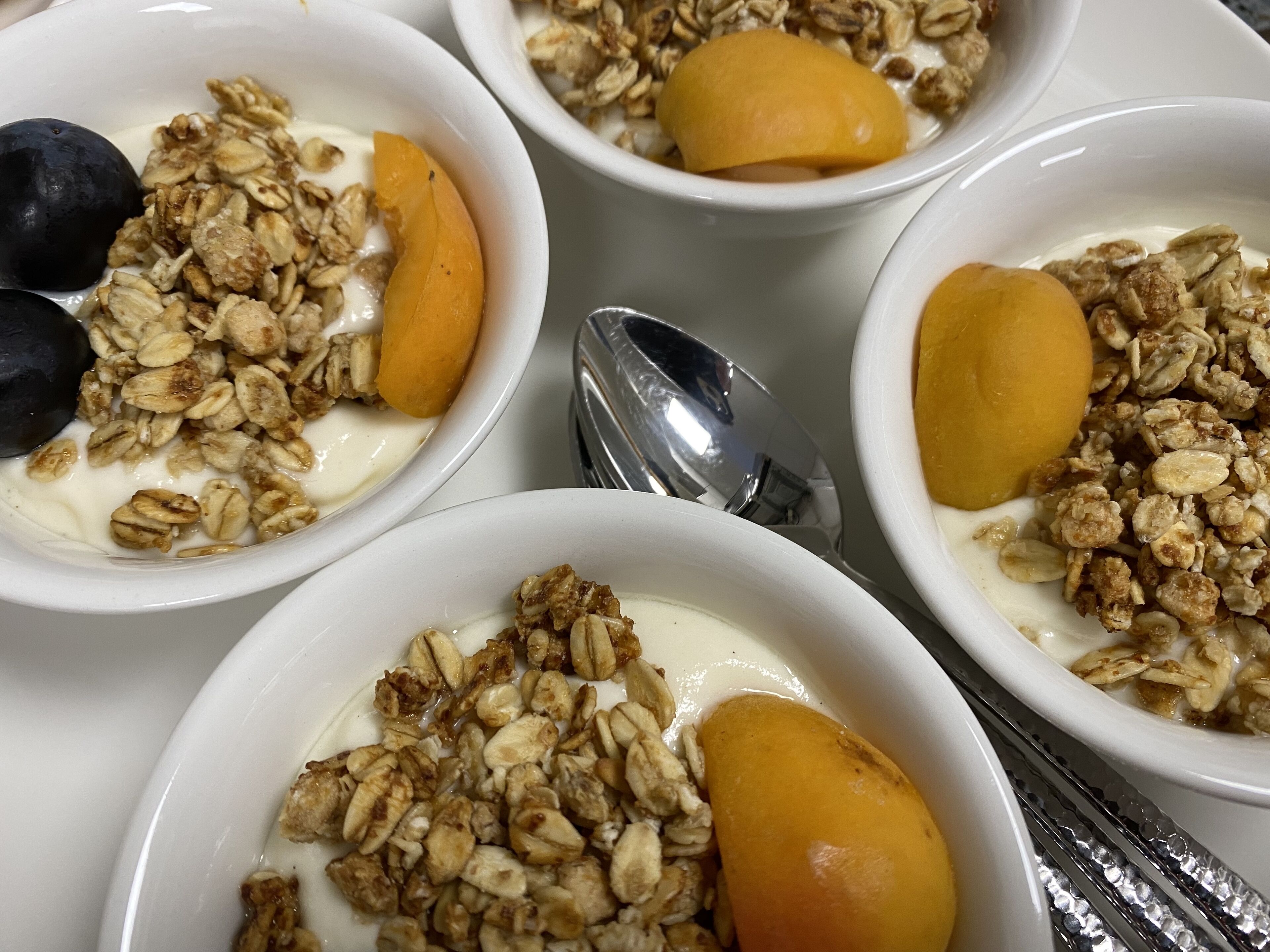 Cuatro tazones de yogur coronados con granola y fruta.
