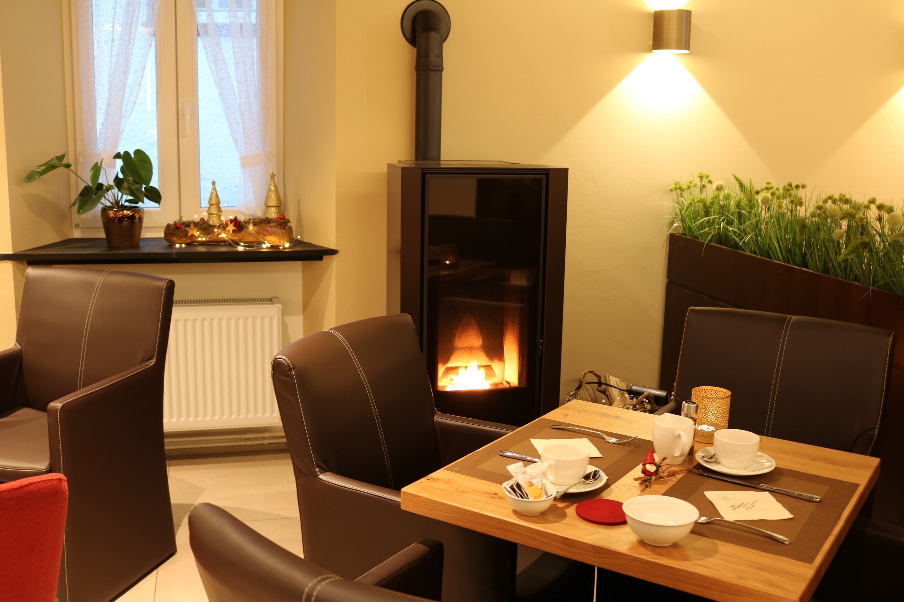 Una habitación acogedora con chimenea, sillones de cuero y una mesa de comedor dispuesta con platos, tazas y cubiertos.