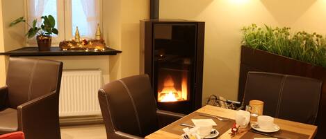 Una habitación acogedora con chimenea, sillones de cuero y una mesa de comedor dispuesta con platos, tazas y cubiertos.