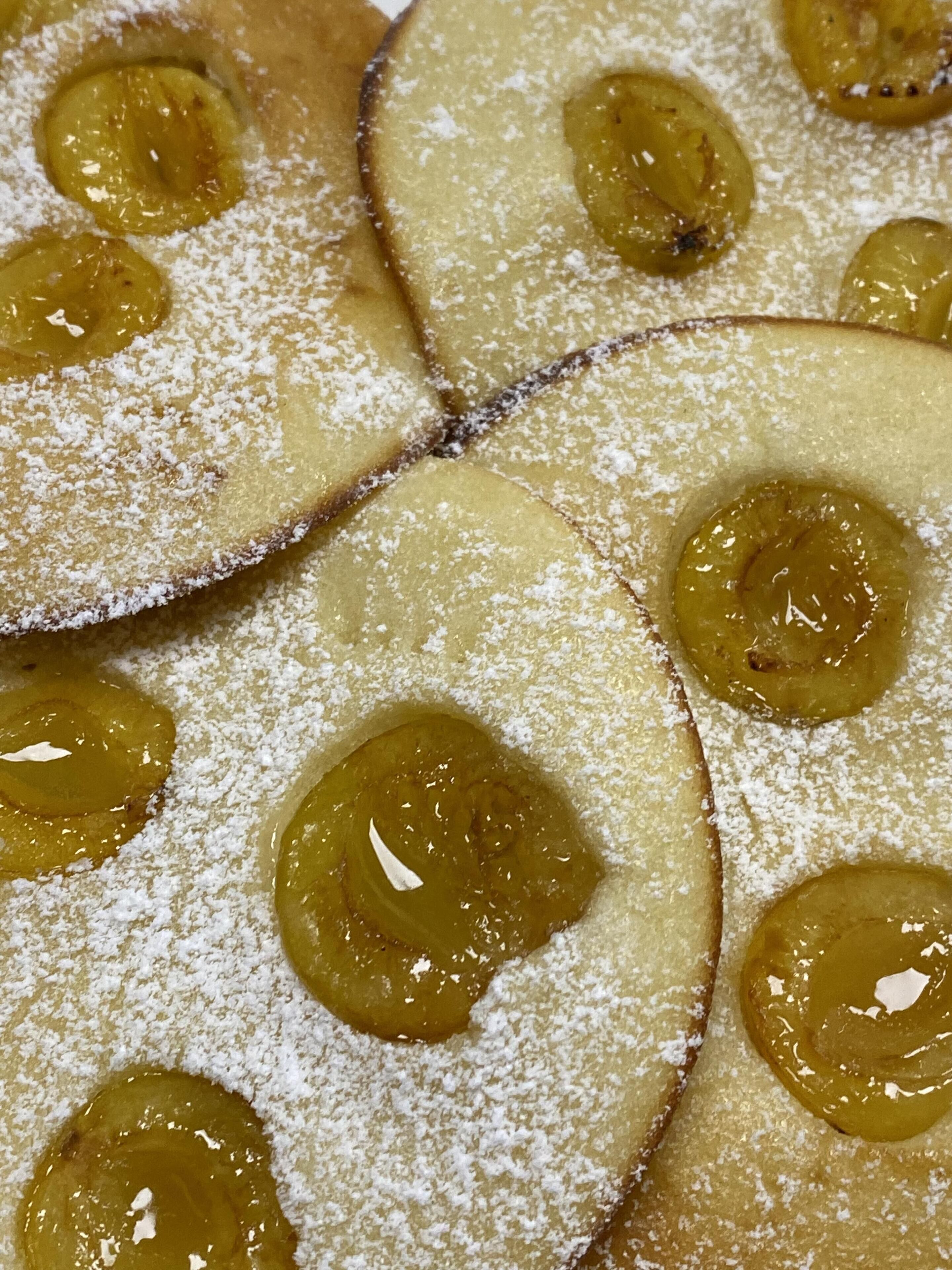 Primer plano de un postre con fruta en rodajas y azúcar glas.