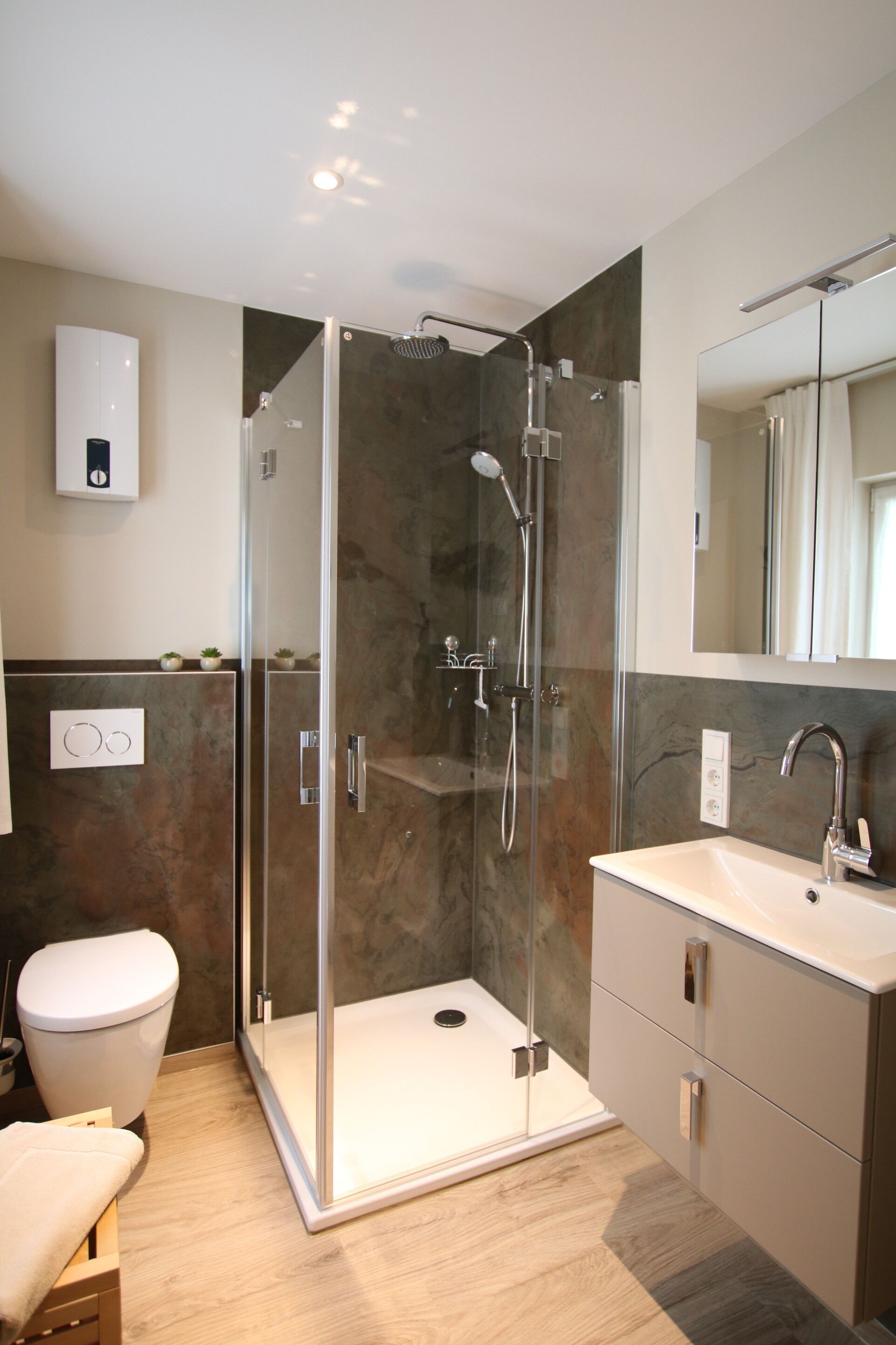 Une salle de bain moderne avec une douche à parois de verre, un lavabo blanc et un miroir au-dessus du lavabo.