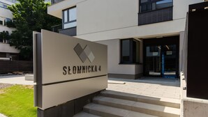 L’entrée d’un immeuble, avec une plaque indiquant « Slomnicka 4 » et un escalier menant à l’entrée.