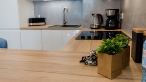 Une cuisine moderne avec un plan de travail en bois, un évier, une machine à café et une plante dans un sac en papier étiqueté « Jardin d’herbes aromatiques ».