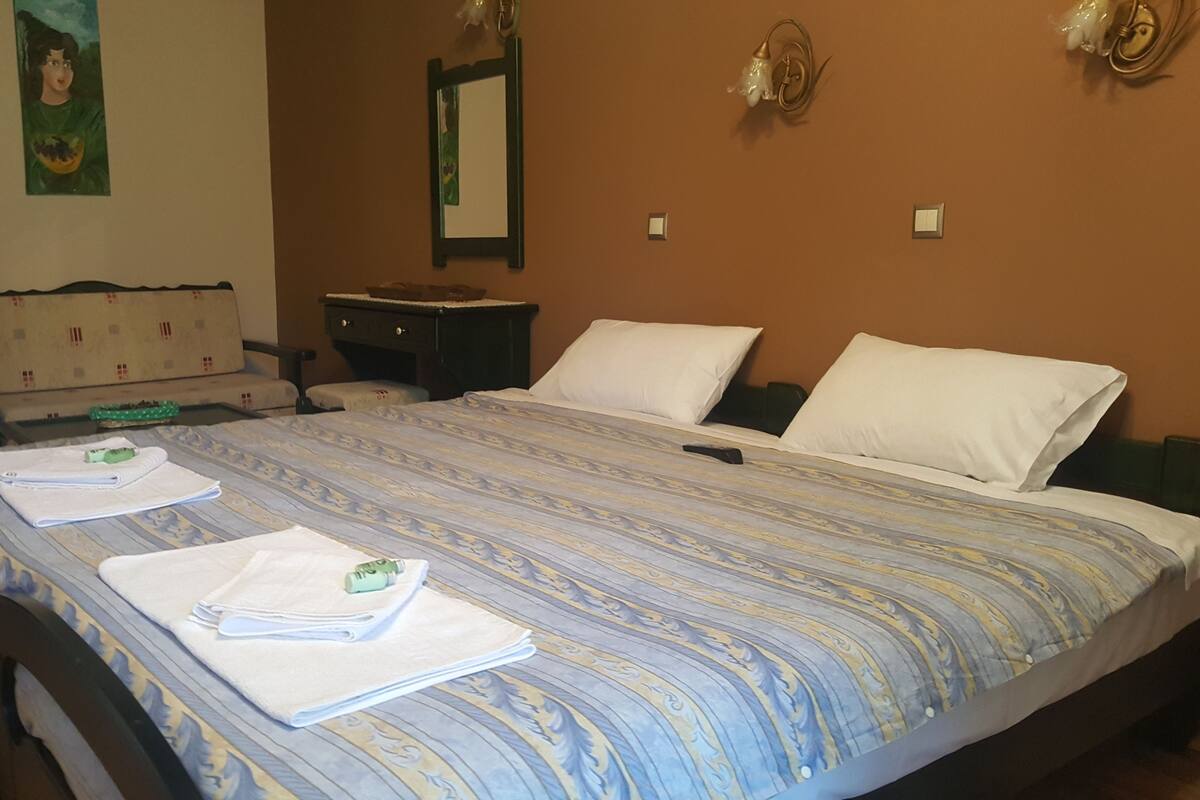 Una habitación de hotel con una cama grande, dos mesitas de noche, un aparador, un espejo y una pared con un cuadro.